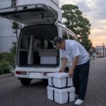 夕方の街に停まる配達用の白い軽バン