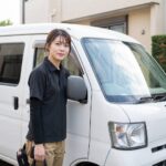 軽バンのそばに立つ女性ドライバー