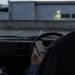 駐車場に止めた軽バンの運転席でスマホに記録する手元